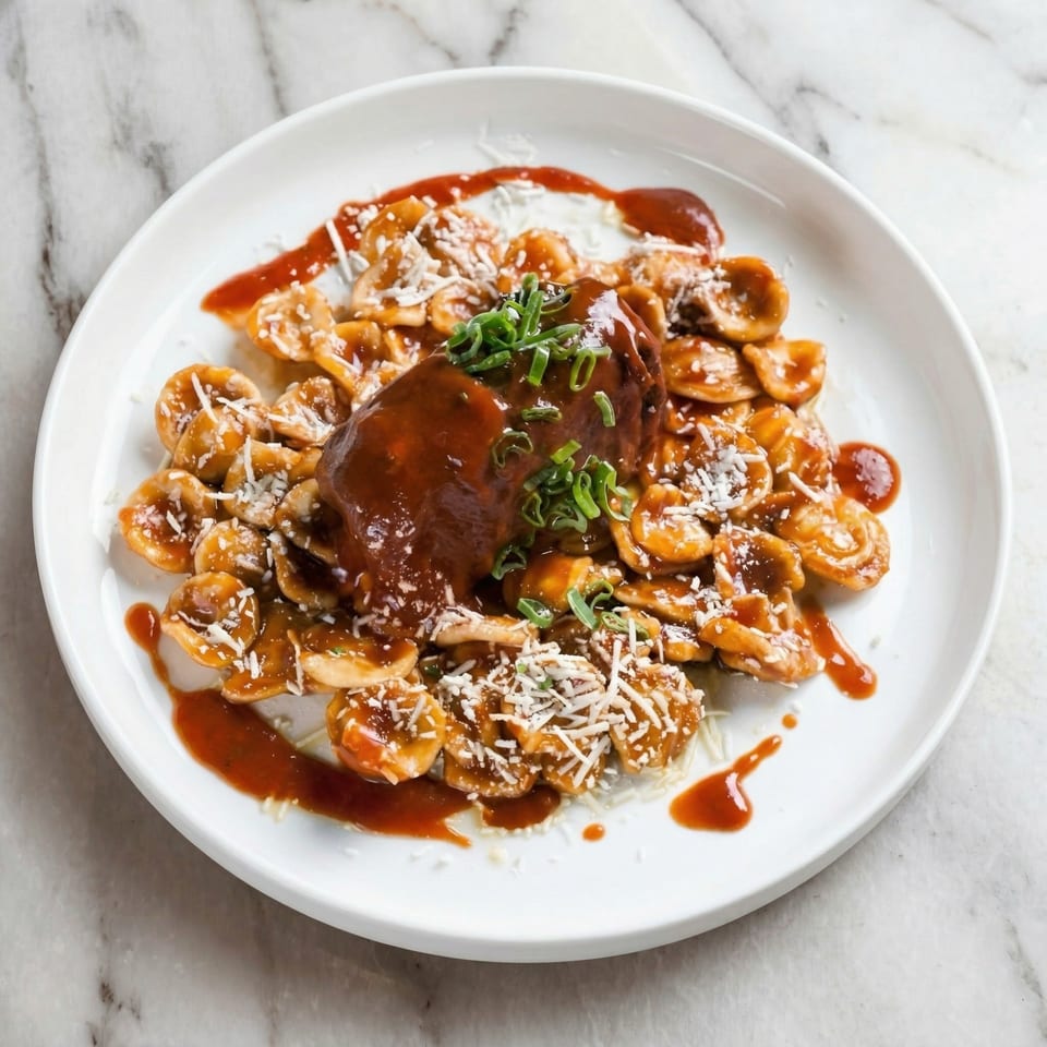 Orecchiette pasta with a rich brown sauce, topped with shredded cheese and green onions.